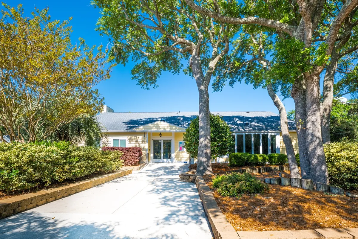 The front entrance of the property is shaded by large trees and surrounded by lush greenery, creating an inviting and serene first impression. The setting is perfect for quiet outdoor moments or gathering with loved ones.
