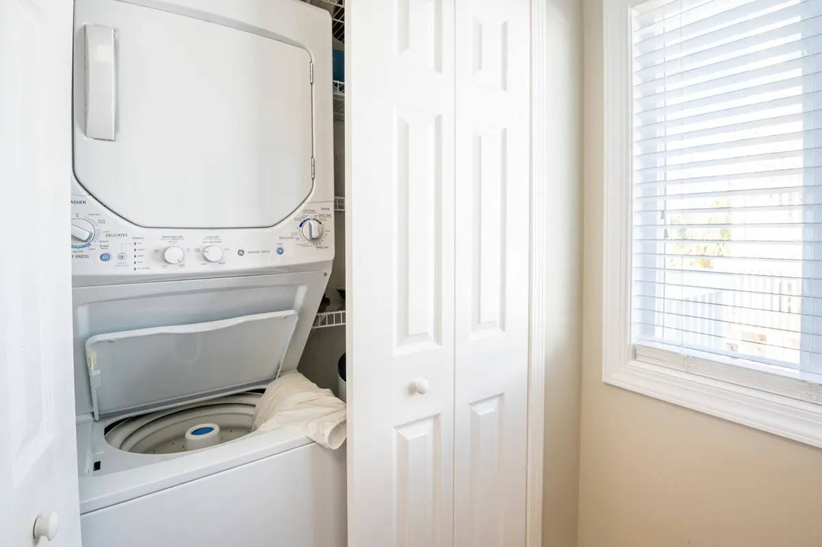 A practical, well-organized laundry area featuring a washing machine and dryer beneath a window. The layout is tidy and accessible, conveying cleanliness and convenience.