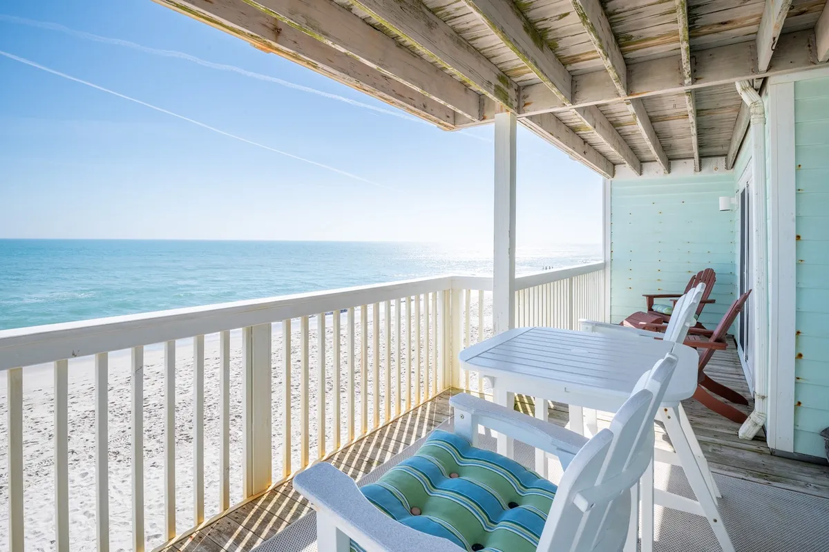A cozy outdoor seating area on a balcony or patio with wooden beams, comfortable furniture, and sweeping views of the ocean. The inviting space suggests time spent relaxing after outdoor exploration, with direct access to fresh air and natural vistas.