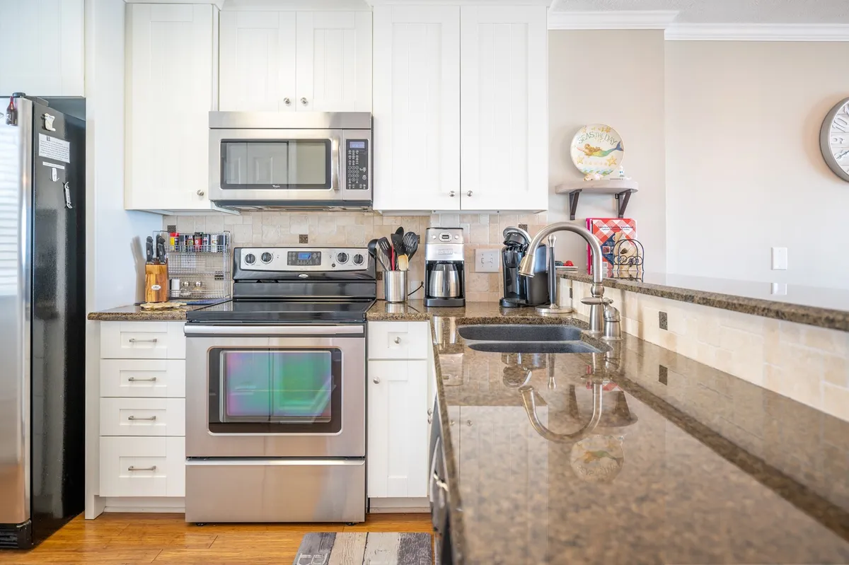A modern kitchen featuring stainless steel appliances, a spacious kitchen island, and granite countertops. The open layout is conducive to group cooking, meal prep, and casual bar seating, making it easy for families to gather and socialize while preparing food.